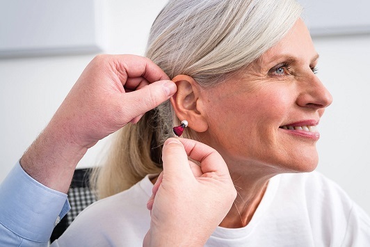 Ältere Frau bekommt ein Hörgerät eingesetzt, Hörakustik und Hörhilfe Beratung.